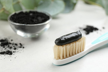 Fototapeta na wymiar Toothbrush with natural bristles and charcoal paste on white table, closeup. Space for text