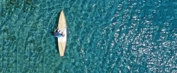 Aerial drone ultra wide photo of fit unidentified man practising in SUP board or Stand UP Paddle...