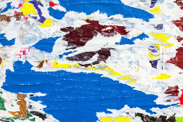 Closeup blue, white and yellow torn and ripped old paper posters and placards layers on urban...