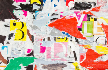 Urban street billboard with torn and peeling old shabby paper posters and placards texture...