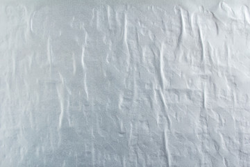 Gray silver gloss wavy paper poster glued on rough surface texture background.