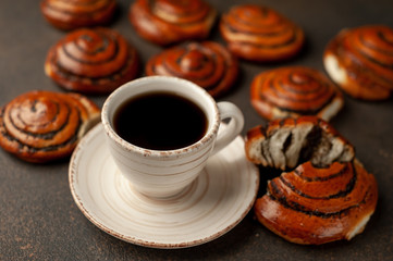 coffee and a lot of buns with poppy seeds on a stone background