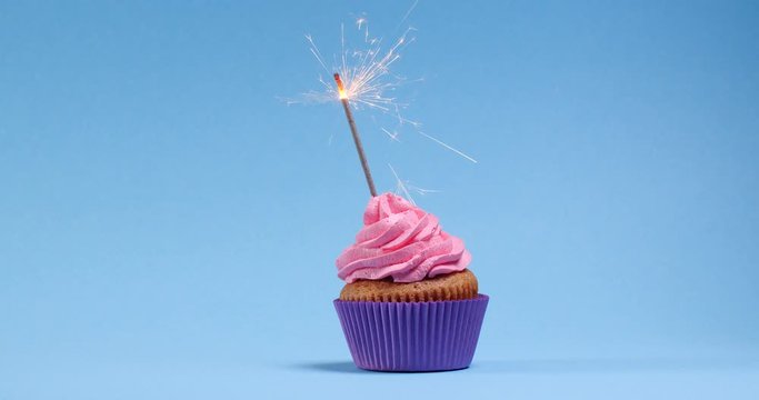 Woman lighting sparkler on blue background, closeup