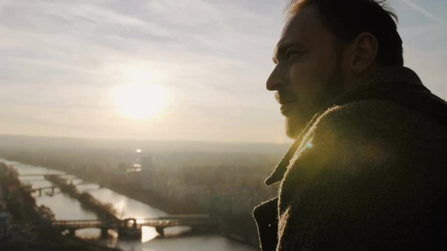 Cinematic close-up portrait of young happy smiling Caucasian man at Eiffel Tower, Paris sunset sky panorama slow motion.