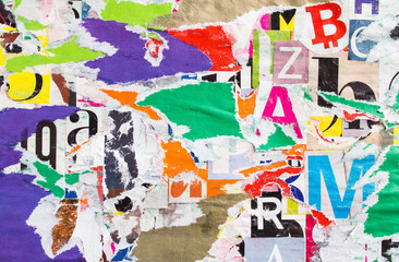Torn and peeling old paper posters layers on billboard with dirty glue stains. Colorful collage...