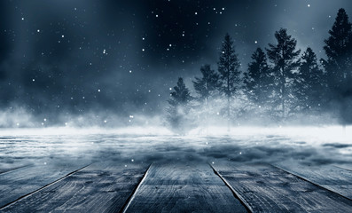 Winter background. Winter snow landscape with wooden table in front. Dark winter forest background at night. Snow, fog, moonlight. Dark neon night background in the forest with moonlight.