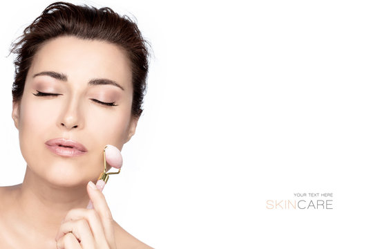 Beautiful woman with healthy fresh clean skin using a face roller massager