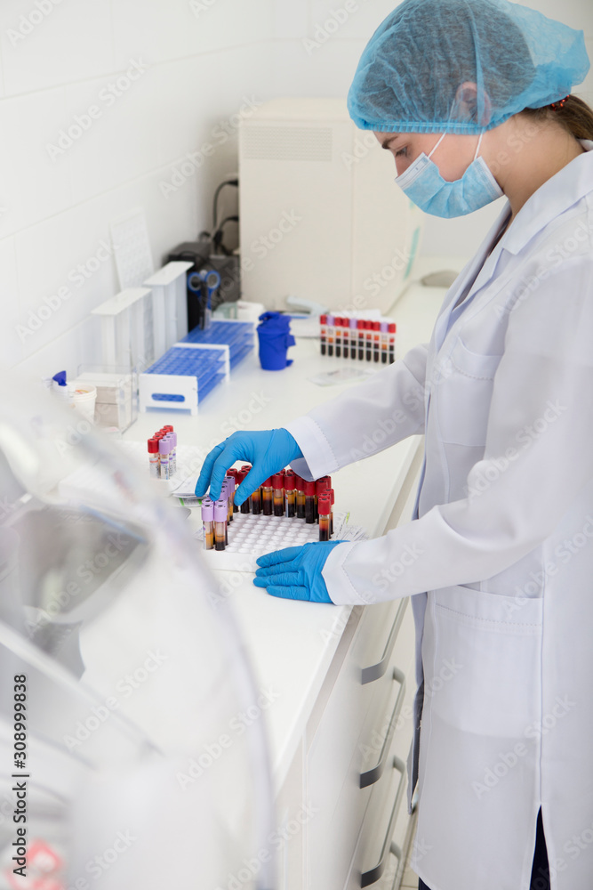 Poster young lab assistant sorting blood in test tubes for analysing