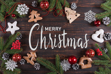 Inscription, Merry Christmas and Happy New Year. Christmas, Fir-trees, handmade ornaments and gingerbread cookies on a wooden table, copy space, top view.