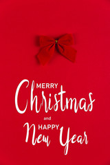 The inscription, Merry Christmas and Happy New Year. Bow on a red background, Christmas concept, copy space.