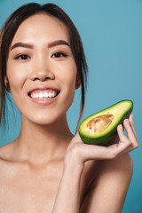 Portrait of half-naked asian woman holding avocado and smiling