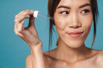 Portrait of half-naked asian woman holding dropper and smiling