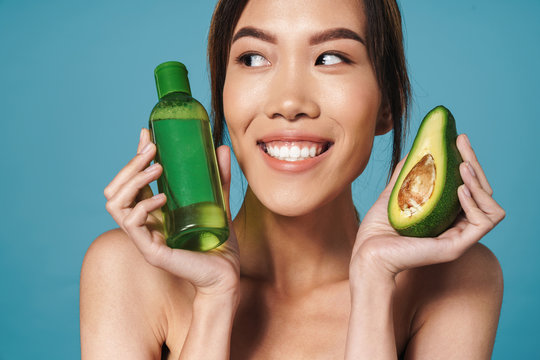 Portrait Of Half-naked Asian Woman Holding Avocado And Bottle Of Lotion