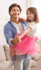 Joyful father and daughter dancing waltz at home