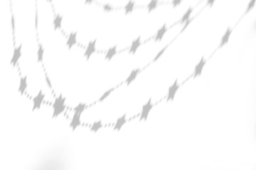 Organic drop shadow of a festive garland of stars on a white wall, overlay effect for photo and mockups.