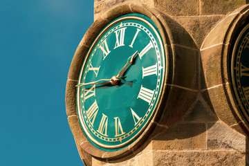 Tower clock with roman numerals against blue sky