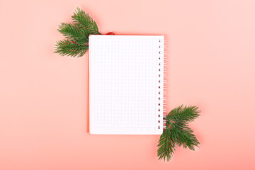 Pink christmas background. Notebook for recording Christmas spending. Two spruce twigs.