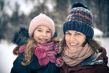 Little girl and her mother playing outdoors at winter day. Active winter holydays concept.