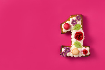 Number one cake decorated with flowers and cookies on pink background. Copy space	