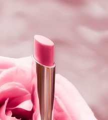 Pink lipstick and rose flower on liquid background, waterproof glamour make-up and lip gloss...