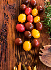 rustikaler holztisch mit bunten tomaten, rosmarin und einem holzlöffel