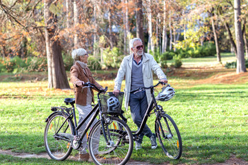 Senior couple with bycicles and helmets in park