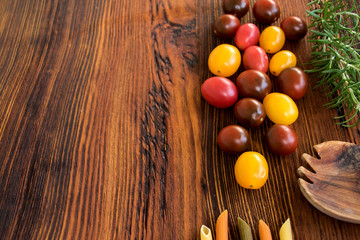 bunte kleine tomaten mit rosmarin und nudeln auf einer rustikalen holzplatte