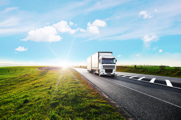 Arriving white truck on the road in a rural landscape at sunset