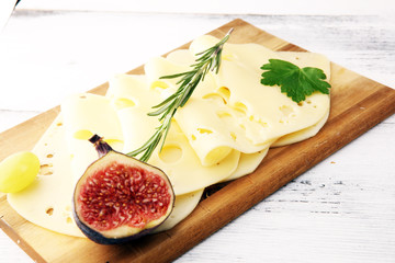 cheese slices on wooden tray with parsley. gauda cheese