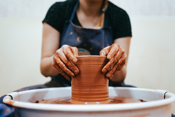 Woman is engaged of pottery. Potter behind the potter's wheel forms clay to create ceramic dishes