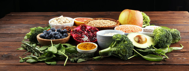 Healthy food clean eating selection: fruit, vegetable, seeds, superfood, cereals, leaf vegetable on rustic background