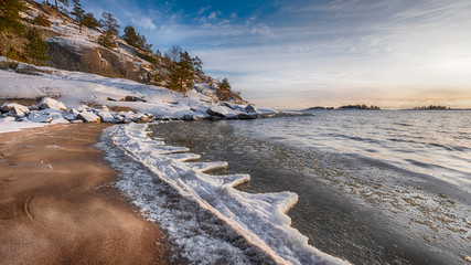 The first ice  off the coast on the water in Lake Ladoga at dawn with fresh snow in winter
