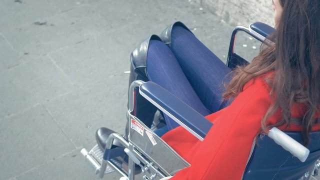 young beautiful disabled woman pushing her wheelchair on the sidewalk