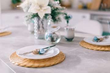 Cutlery and plates neatly placed on the kitchen table with Christmas decor