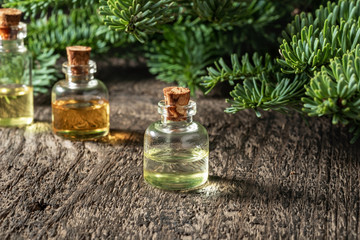 A bottle of fir essential oil with fresh fir branches