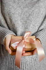 Woman holds a Christmas present in hands. Happy holiday, gift box close-up. Surprise for Boxing day, Christmas and New Year party. Magic time. Celebration winter event. Wrapping paper, toys and ribbon
