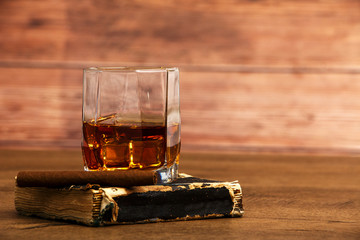 Whiskey with ice or brandy in a glass and a square carafe on an old wooden background. Whiskey with ice in a glass. Whiskey or cognac. Selective focus.