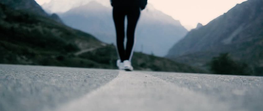 the girl walks along the line of the road where a very beautiful landscape mountains