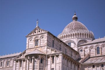 Fototapeta na wymiar Close up on exterior of Pisa Cathedral. Visible front facade and dome, blue sky. Famous landmark. Tuscany. Italy. No people. 