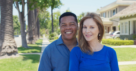 Fototapeta premium Portrait of senior couple smiling on sidewalk in suburban neighborhood