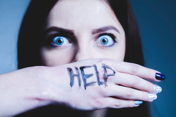 Portrait of young frustrated woman asking for help as symbol of fear and horror. Selective focus on...