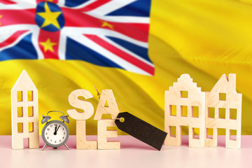 Niue real estate sale concept. Wooden house model with discount tag on national flag background. Copy space for text.