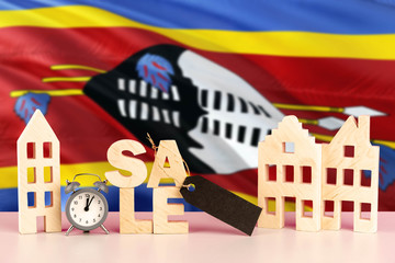 Swaziland real estate sale concept. Wooden house model with discount tag on national flag background. Copy space for text.