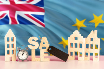 Tuvalu real estate sale concept. Wooden house model with discount tag on national flag background....