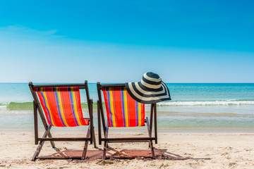 Beach chair and straw hat on beach in outdoors