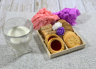 A glass of milk with cookies on a white napkin.