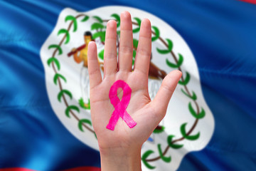 Belize awareness concept. Close-up awareness ribbon painted on palm on national flag background. October Pink day and world cancer day.