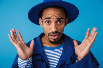 Photo of confused african american man looking at camera with hands up