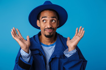 Photo of confused african american man looking aside with hands up