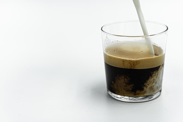pouring milk into glass of coffee